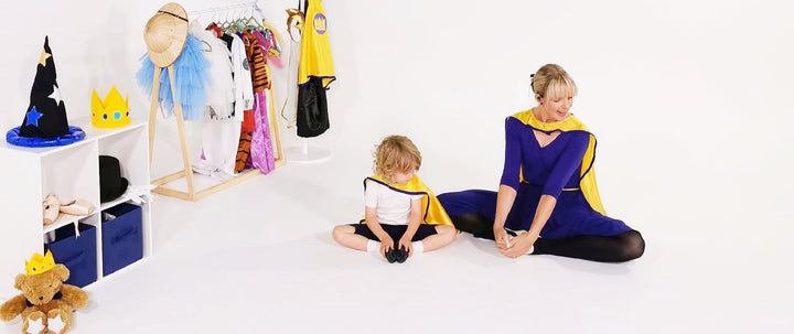 Early childhood ballet teacher and preschool boy dancer sitting in a ballet stretch position working on improving their hip flexibility. Educational dance opens children to new learning experiences and makes them body aware.